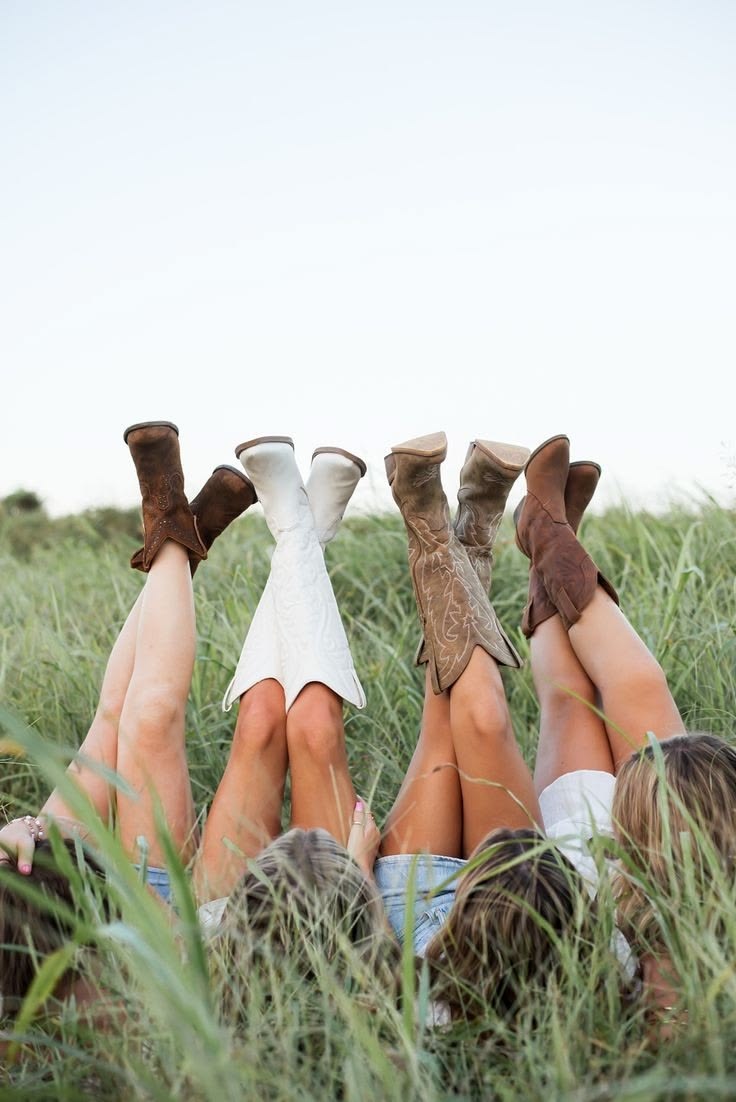 Botas de cowgirl erguidas sobre o capim alto no campo, em tons terrosos e creme