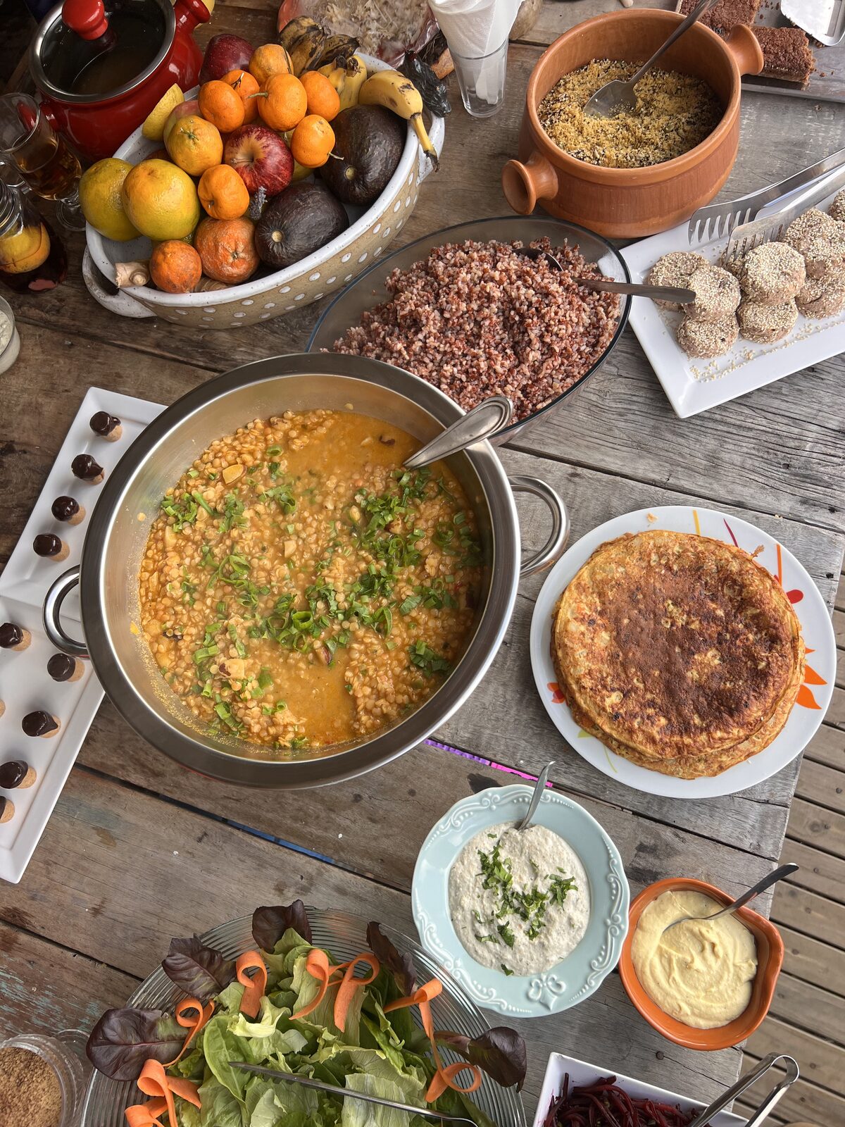 Mesa de madeira com pratos saudáveis, frutas frescas, salada e patês ao ar livre